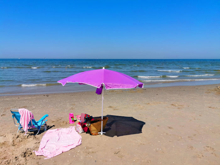 Deck chairs on beach against clear blue sky