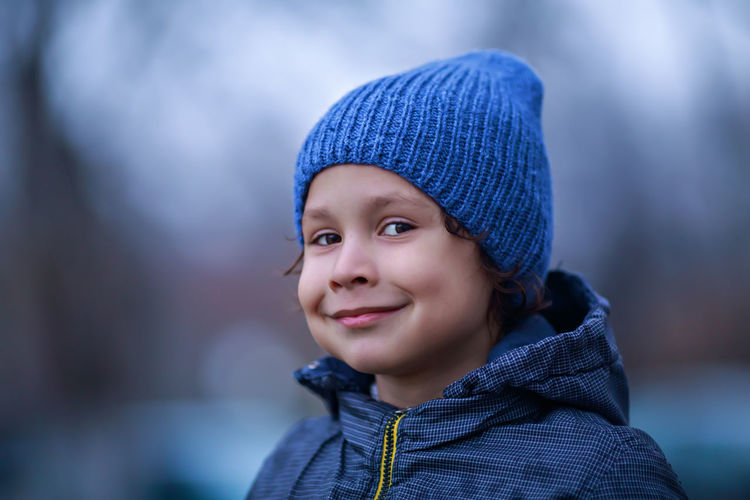 Close-up portrait of smiling boy looking away during winter