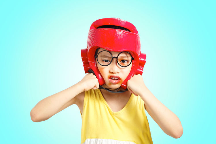 Portrait of boy wearing boxing head protector against blue background