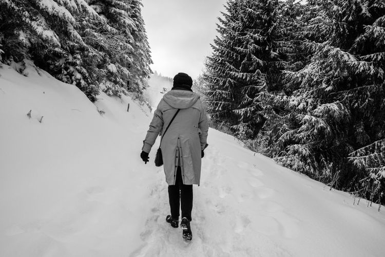 Rear view of woman walking on snow covered forest