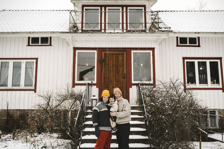 Portrait of happy lesbian couple with daughter against house during winter
