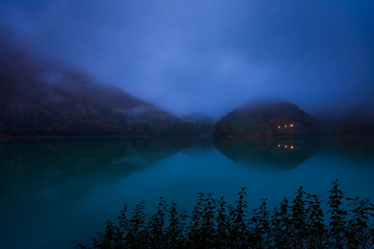 Scenic view of lake against blue sky at dusk