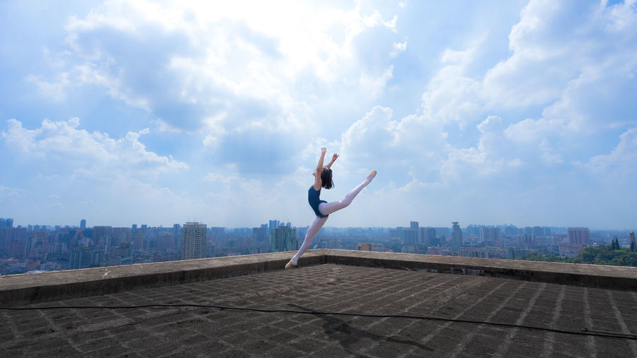 Woman with arms raised against sky