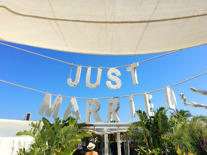 Low angle view of just married text hanging on ropes against clear sky