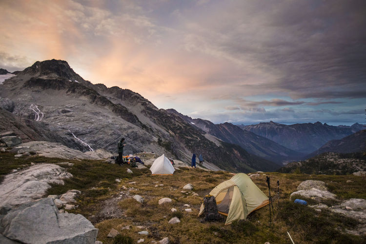 Climbers camping in alpine meadow below mountain.