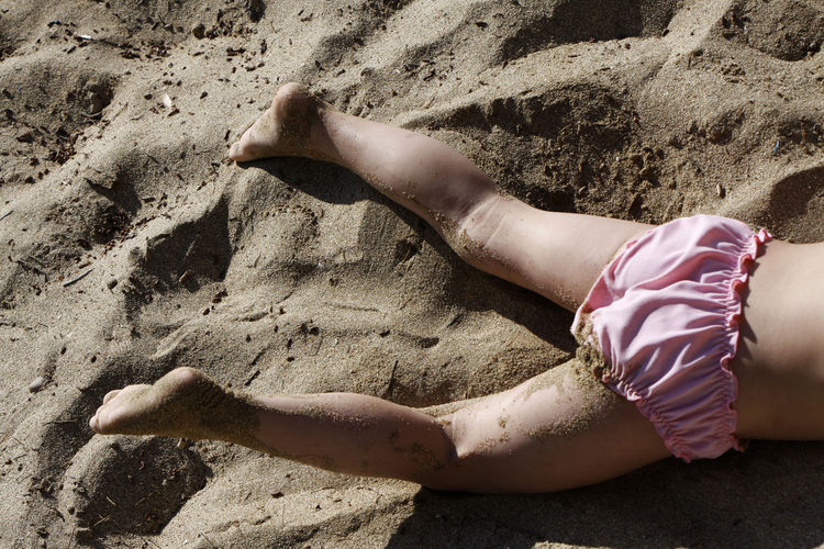 Low section of woman lying on sand