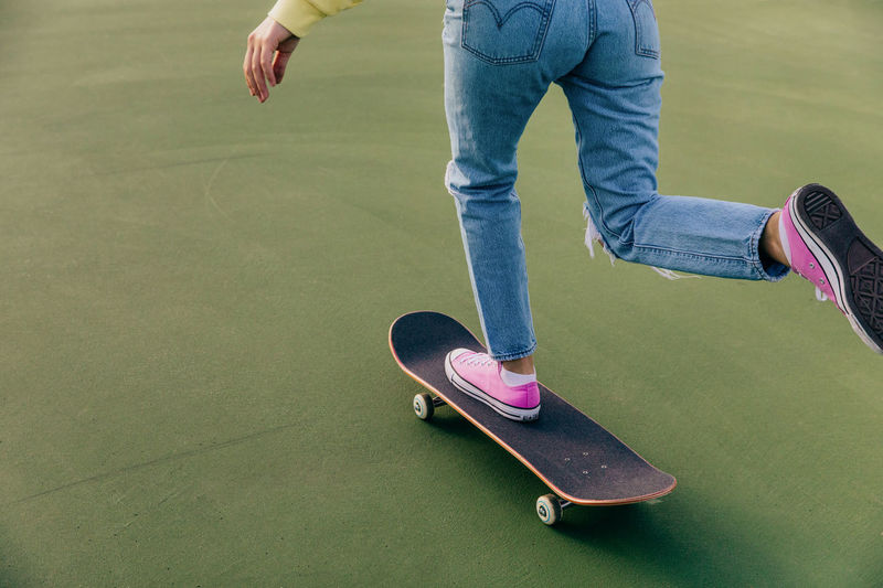 Low section of girl skateboarding on tennis court