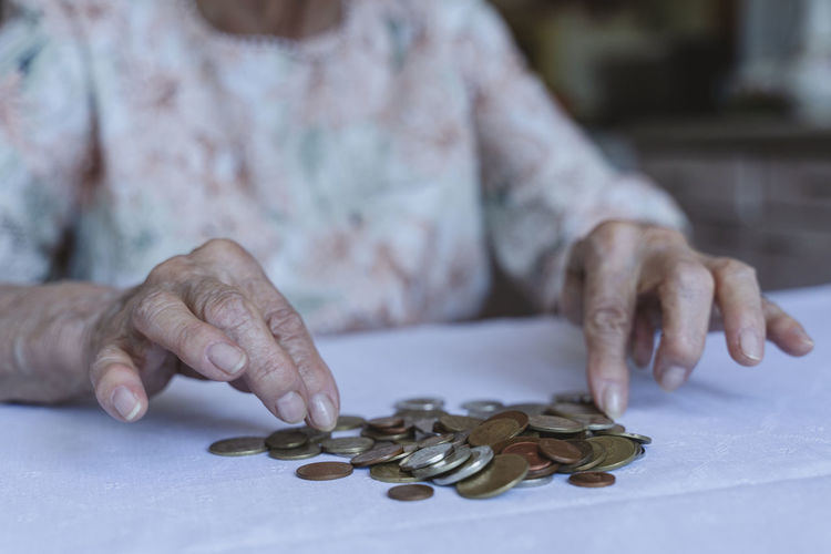 Senior woman counting coins on table at home