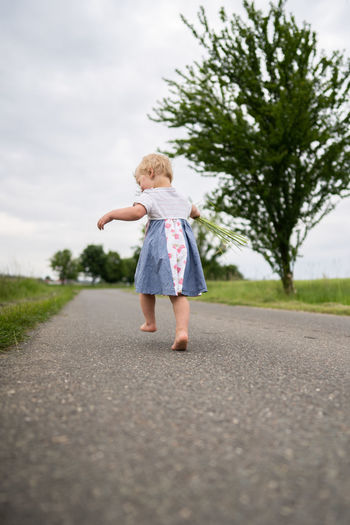 Full length of girl running on road against sky