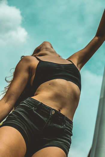 Low angle view of young woman against sky