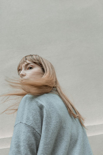 Rear view of woman with blond hair against wall