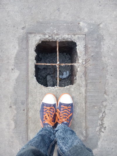 Low section of man standing by broken manhole