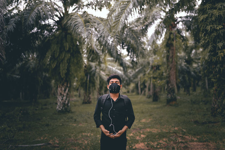 Portrait of young man wearing mask standing in forest