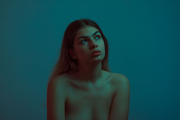 Thoughtful young woman against blue background