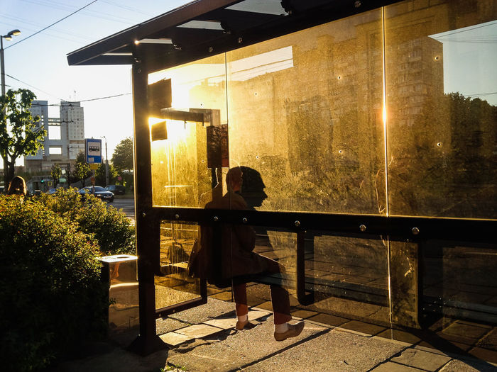 Rear view of woman sitting against built structure