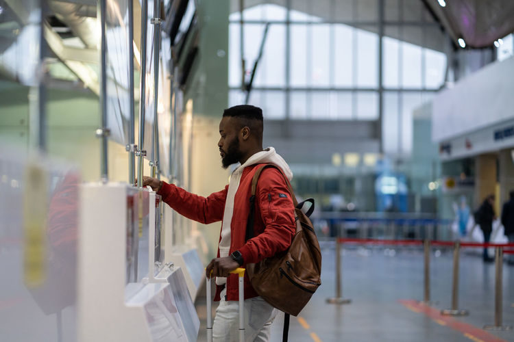 African young man traveler showing documents at check-in counter in airport. border control