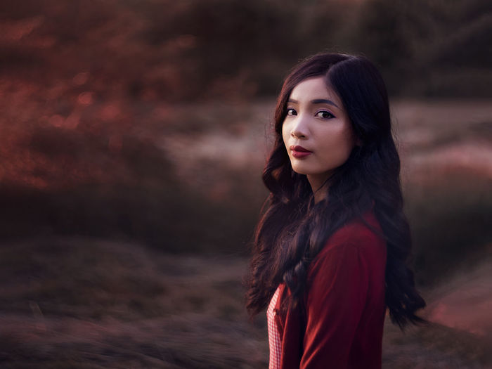 Portrait of young asian woman standing outdoors at golden hour