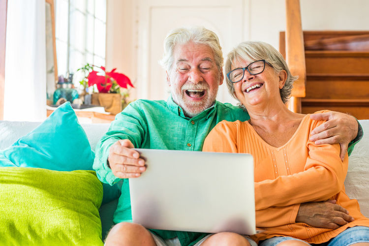 Smiling couple using laptop while sitting at home