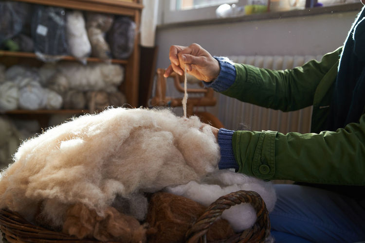Midsection of person holding wool in basket at home