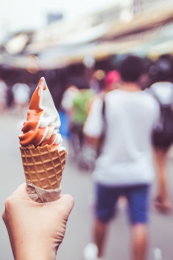 Hand holding melting ice cream waffle cone in hand on summer background