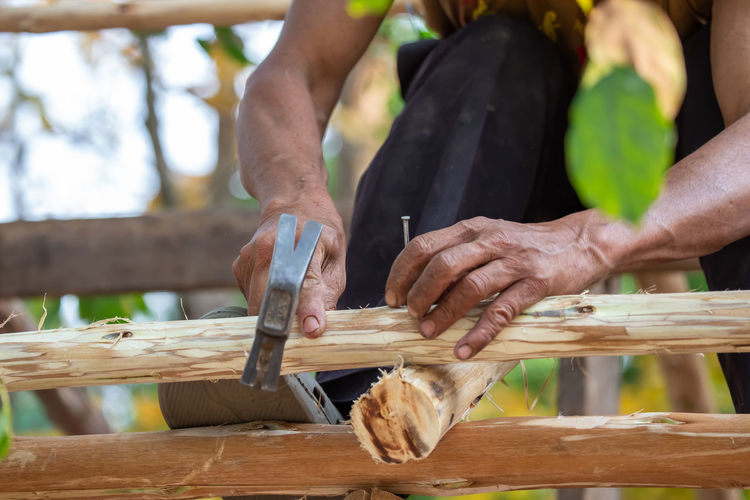 Close-up of a man hammering nails on a eucalyptus wood roof frame. house design using