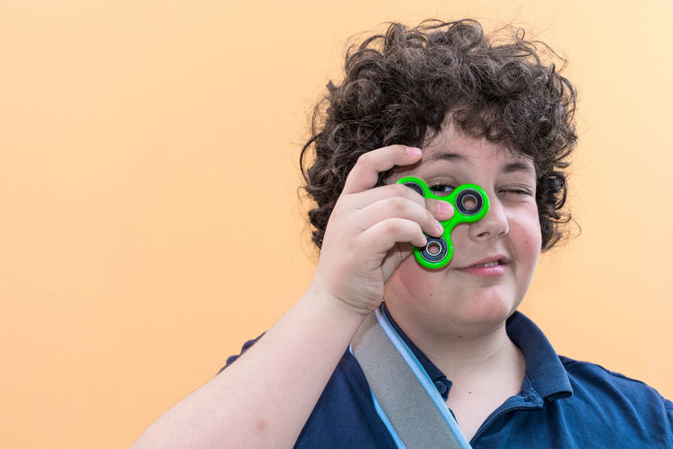 Portrait of boy holding fidget spinner against colored background