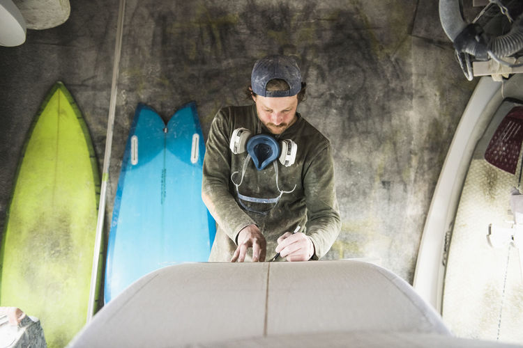 Surfboard shaper measuring a new design