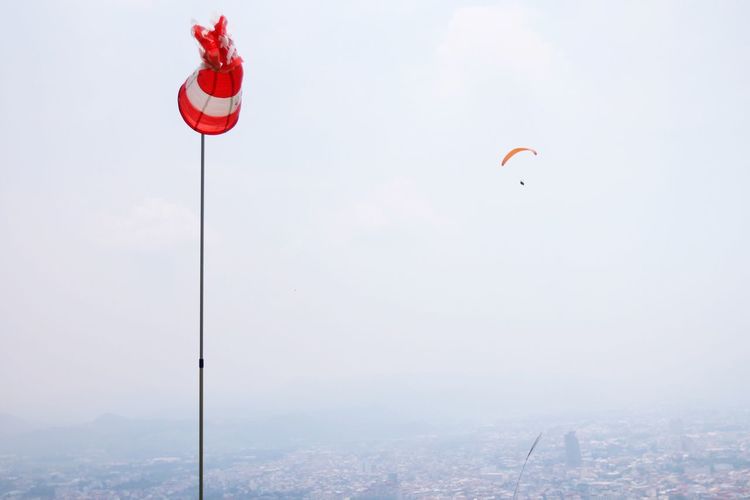 Low angle view of windsock against parachute in sky