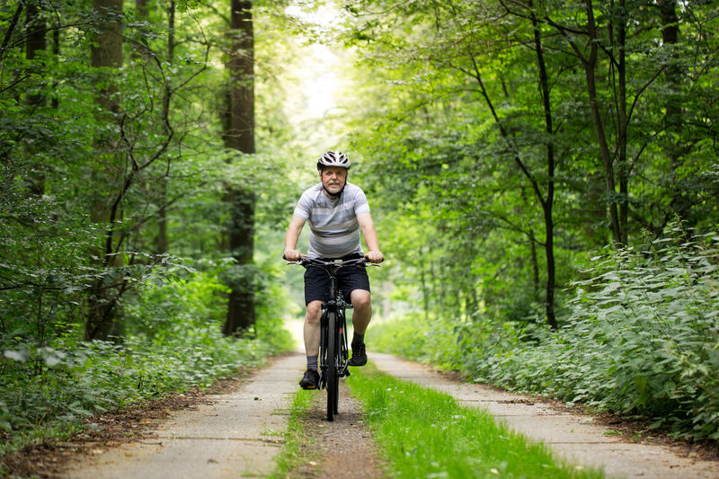Man riding bicycle on footpath in forest