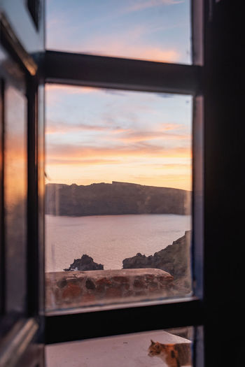 Sea seen through window during sunset