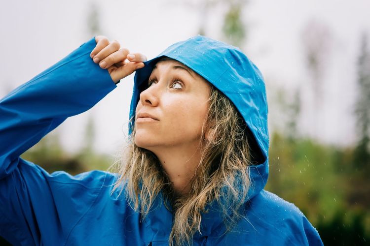 Woman standing in the rain with a raincoat on looking up at the sky