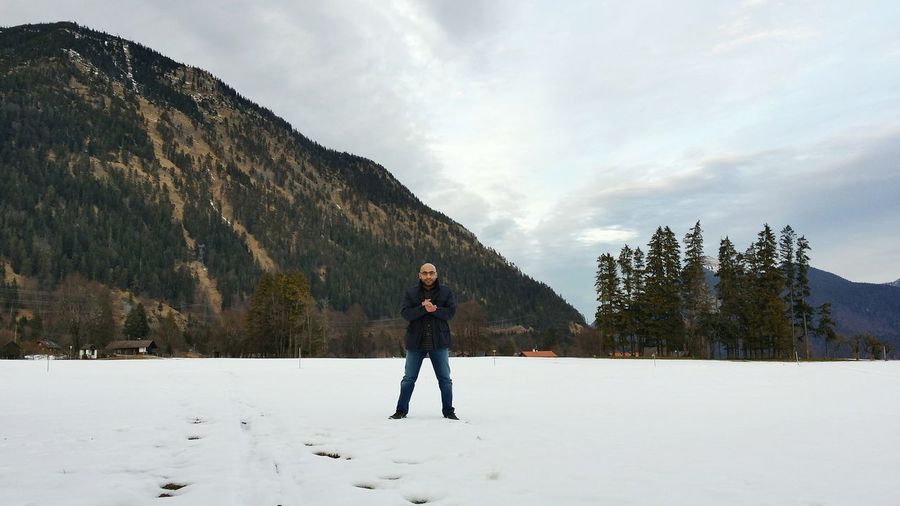 Full length portrait of man standing on snowfield against mountain