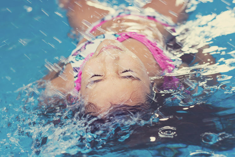 Girl enjoying in swimming pool with closed eyes
