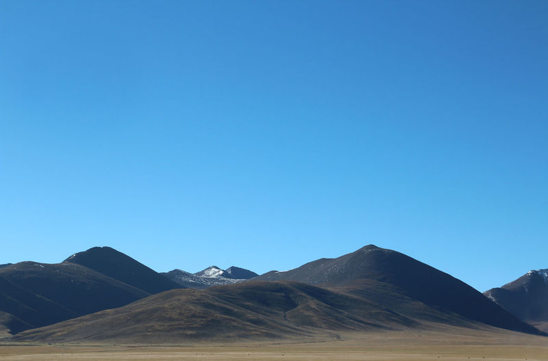 Scenic view of mountains against clear blue sky