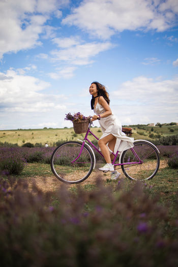Happy asian woman on bike travel in lavender field