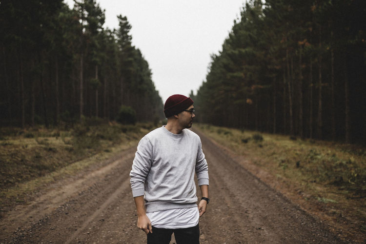 Young man standing on dirt road amidst trees