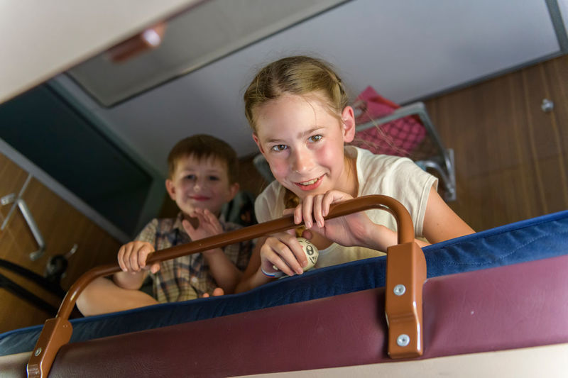 Low angle portrait of siblings sitting on bunkbed at home