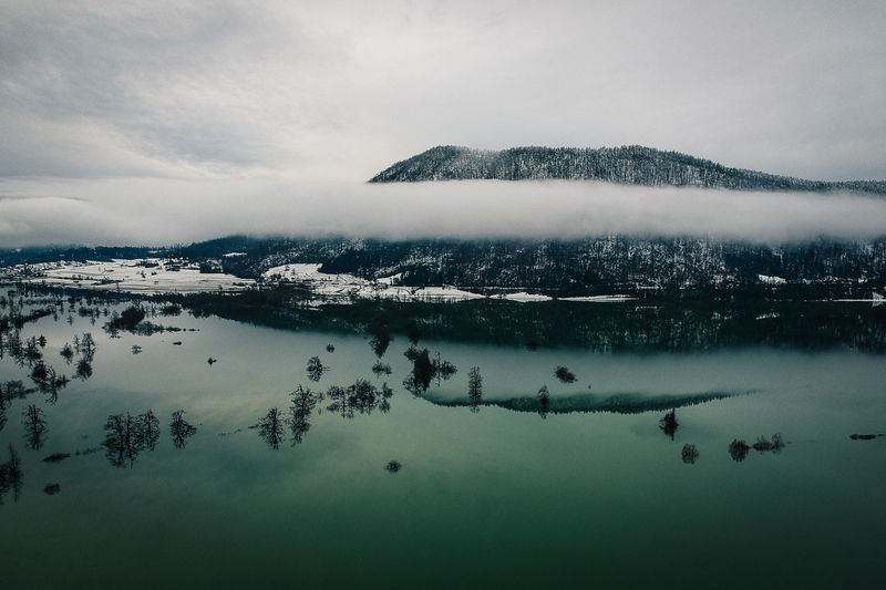 Aerial view of lake by snowcapped mountain against sky