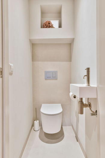 Toilet placed at wall in light small bathroom at home
