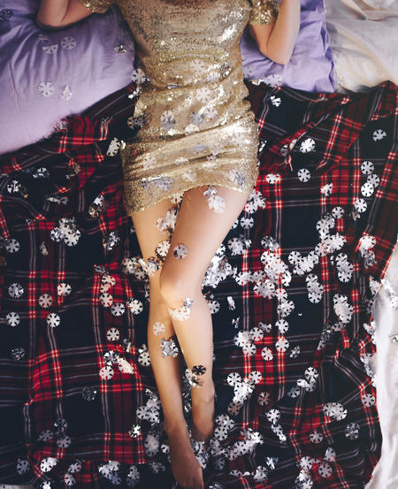 Low section of woman lying with confetti on bed