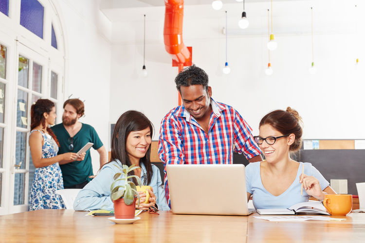 Colleagues discussing over laptop in office