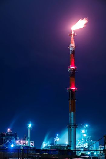 Low angle view of oil refinery tower by night 
