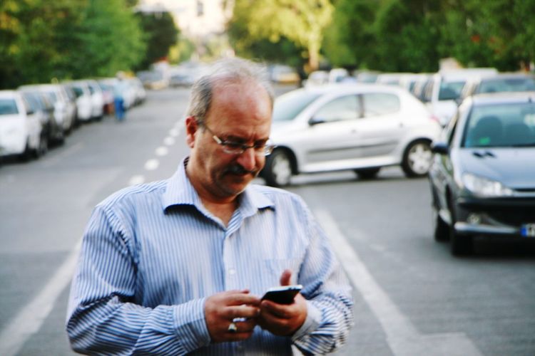 Man using mobile phone while standing on road