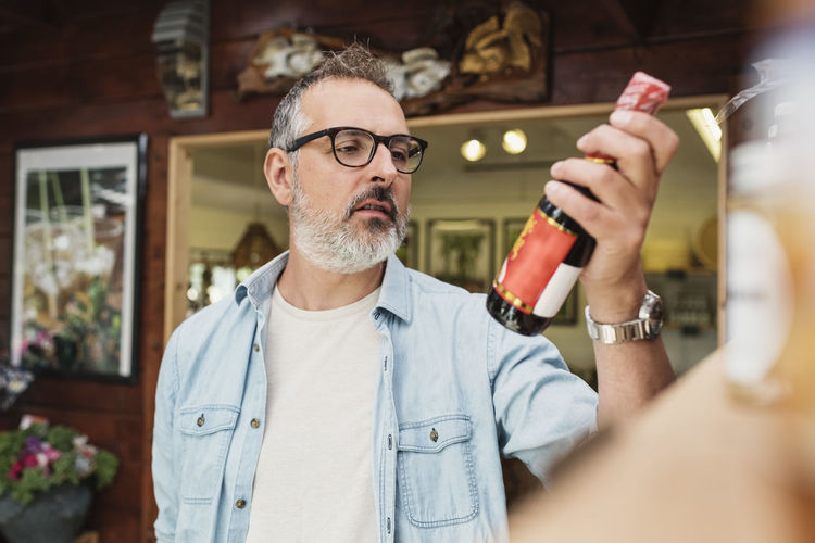Mature man checking information on bottle while shopping at store