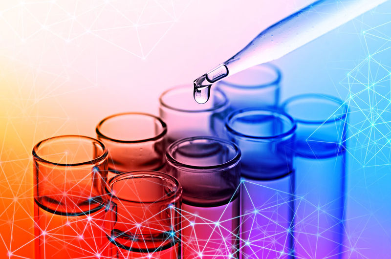 Digital composite image of liquid dripping from pipette into test tube with molecular structure