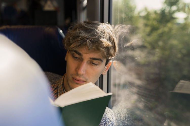 Young man reading book in a train