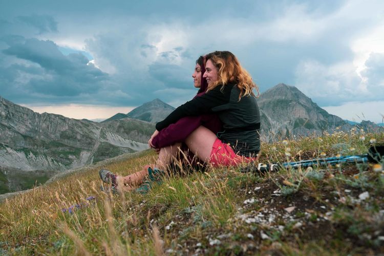 Woman sitting on a italian mountain against sky.
