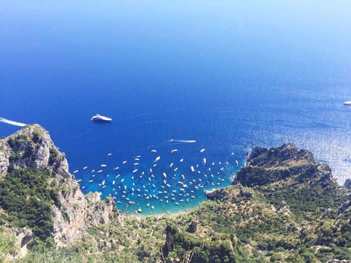 Aerial view of boats on blue ocean by mountain