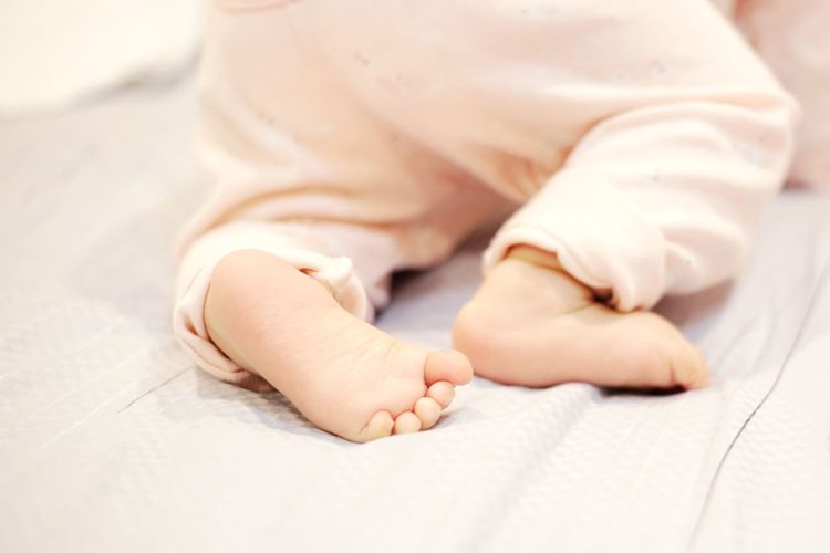 Low section of baby feet on bed