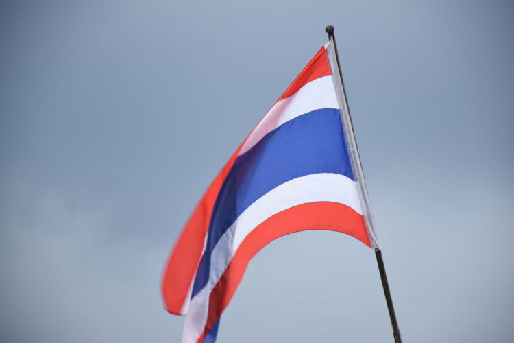 Low angle view of thai flag against blue sky